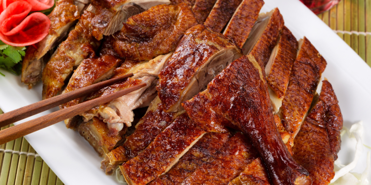 Pieczona kaczka po staropolsku podana na talerzu z kluskami i buraczkami.